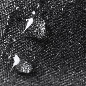 A close-up of a textured black fabric with water droplets on its surface, showcasing its water-resistant features.