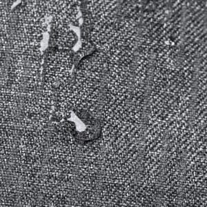A close-up of a textured grey fabric with water droplets on its surface, illustrating its water-resistant properties.