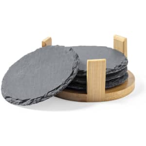 A set of circular grey slate coasters displayed on a wooden holder. The design features a minimalistic style.