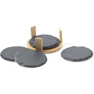 A set of four grey slate coasters arranged beside a round wooden holder.