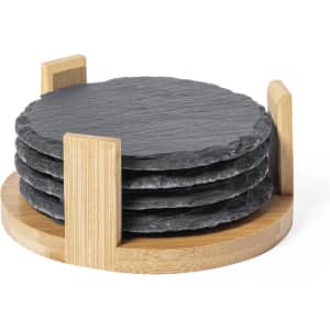 A set of four round black slate coasters stacked in a bamboo holder.