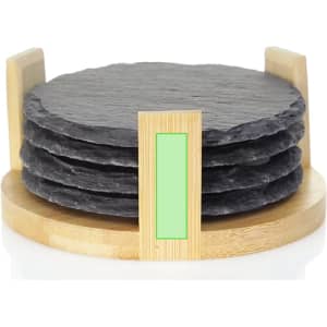 A set of four round, black slate coasters stacked in a bamboo holder.