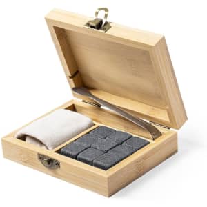 A bamboo box containing grey stone ice cubes, a silver tong, and a cloth. The lid is slightly open.