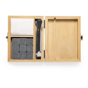 A bamboo box containing stone ice cubes, a cleaning cloth, and a stirring tool. The cubes are grey, and the box has a natural wood finish.