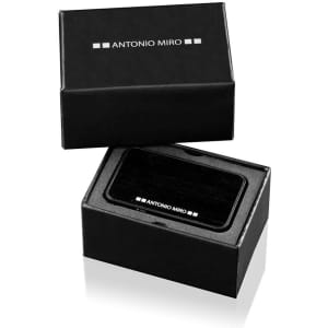 A sleek black card reader in an open black box with a logo, resting on a reflective surface.