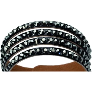 A set of three black bracelets featuring shiny black stones, displayed against a soft brown background.