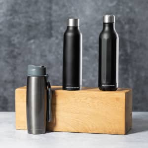 A drink bottle collection featuring three stainless steel vacuum bottles in black and grey, displayed on a wooden block.