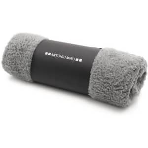 A rolled grey blanket with fluffy texture, secured with a black band featuring a logo.