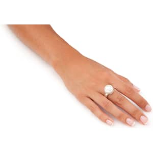 An adjustable silver ring featuring a large white pearl, worn on a hand with manicured nails.