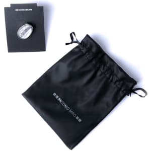 An adjustable silver ring resting on a black display card, alongside a black drawstring pouch with a logo.