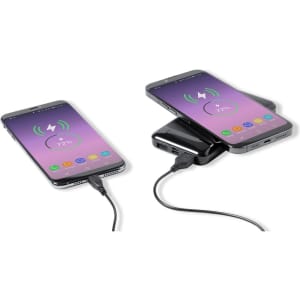 A power bank in black with two smartphones charging, one wirelessly and one via a cable.