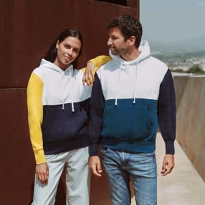 A sweatshirt featuring a colour-block design in white, navy, and yellow, worn by a man and woman. The design includes a hood.