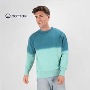 A teal and mint gradient sweatshirt featuring a crew neck and a cotton logo, worn by a smiling model.