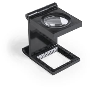 A black magnifier with a hinged design, featuring a circular lens and a square base with measurement markings.