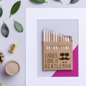 A pencil set featuring wooden pencils in various colours, packaged in a decorative cardboard holder.