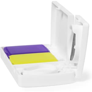 A white pillbox featuring two compartments, one purple and one yellow, with a small cutting tool inside.
