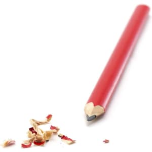 A red pencil lies next to wood shavings, showcasing its sharp tip and vibrant colour.