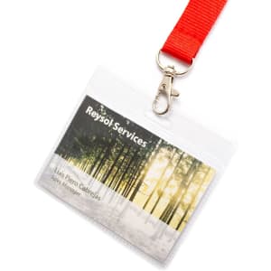 A name badge in a clear holder with a red lanyard. The badge features a nature-themed background.