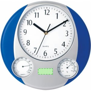 A round wall clock with a blue and silver design features large numbers, a thermometer, and a humidity gauge.