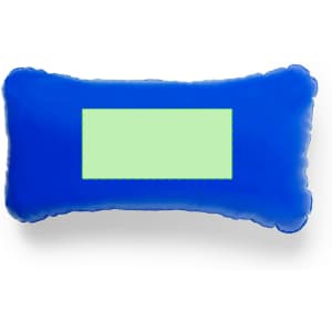 A blue pillow with a rectangular green panel in the centre, featuring a soft, plush texture.