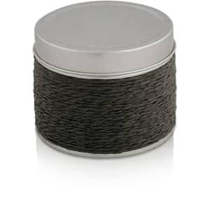 A round, dark grey aromatic candle in a metal tin with a textured rope design around the base.