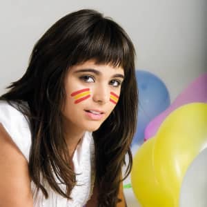 A young woman with dark hair and face paint in red stripes, surrounded by colourful balloons. Contains a logo in the corner.