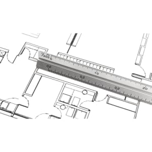 A metallic thirty scale ruler placed over architectural plans, featuring a clear measurement scale.