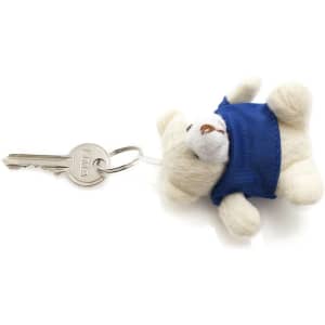 A keyring featuring a small white teddy bear wearing a blue outfit, attached to a key.