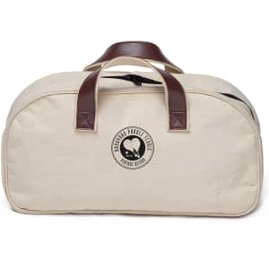 A cream-coloured bag with brown leather handles and a logo on the front. The bag has a zipper closure.
