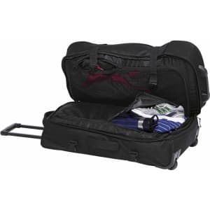 A black wheeled travel bag with multiple compartments, featuring sports shoes, a drink bottle, and clothing inside.