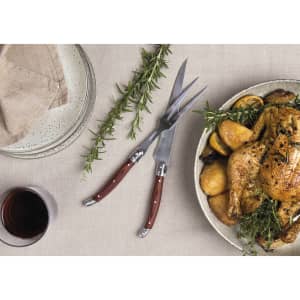A Bordeaux carving set with stainless steel blades and wooden handles, displayed alongside roasted chicken and herbs.