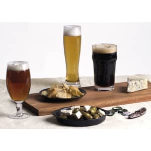 A craft beer glass set featuring three different beers: a dark stout, a pale lager, and an amber ale, alongside snacks.