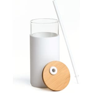 A drink bottle made of clear glass with a white silicone sleeve, a bamboo lid, and a white straw.