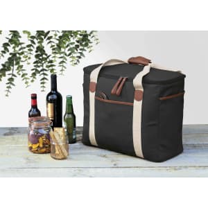 A black cooler bag with tan straps, surrounded by bottles of wine and beer, plus jars with snacks.
