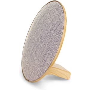 A round Bluetooth speaker in grey fabric with a wooden base, featuring a minimalist design and a logo on the side.