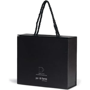 A black box with a handle, containing an espresso set, featuring a logo on the front.