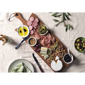 A wooden serving board featuring cured meats, cheeses, olives, pickles, and condiments, with a natural finish.