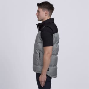 A grey puffer vest with a black collar, featuring a logo and side pockets, worn by a model in profile.