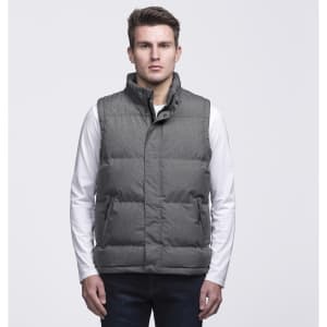 A grey puffa vest with a high collar and buttons, featuring two side pockets and a logo. Model is wearing a white long-sleeve shirt.