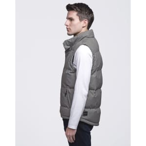 A grey puffer vest displayed on a male model, featuring a high collar and a logo tag.