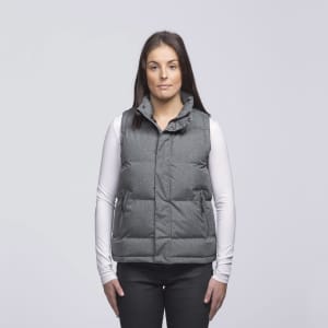 A grey puffa vest with a collar and pockets, worn over a white long-sleeve top. The model stands against a plain background.