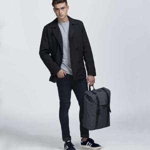 A grey front-side backpack held by a person wearing a black coat, grey shirt, and dark jeans.