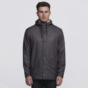 A grey rain jacket with a hood, featuring snap buttons and pockets, worn by a model. It has a logo on the front.