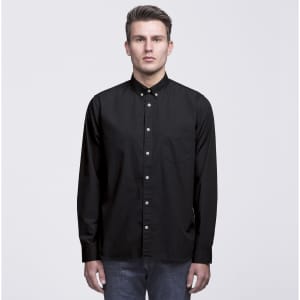 A black button-up shirt with a collar and long sleeves, featuring a chest pocket. It has a logo on the collar.