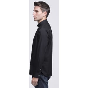 A button-up shirt in black, displayed on a model from the side, featuring a collar and long sleeves.