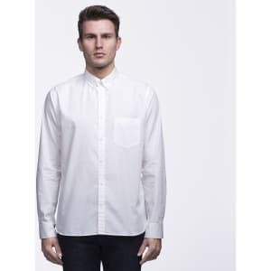 A white button-up shirt featuring a chest pocket, styled with a collar. The model is standing against a plain background.