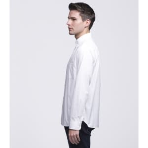 A man wearing a white button-up shirt, viewed from the side, with a simple design and a logo on the fabric.