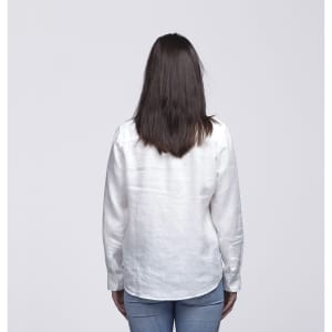 A white linen button-up shirt viewed from the back, worn by a woman with long hair, paired with blue jeans.