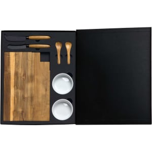 A gourmet cheese board set featuring a wooden board, knives, spoons, and two white bowls, all packaged in a black box.