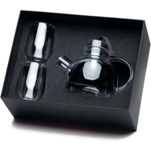 A transparent teapot with two matching cups, all packaged in a sleek black box with textured interior.
